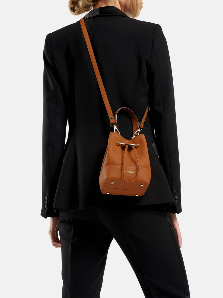 Wearable as a crossbody or carried in the hand, this leather Strathberry drawstring bucket bag is versatile, compact, and perfect for everyday. Collagerie.com