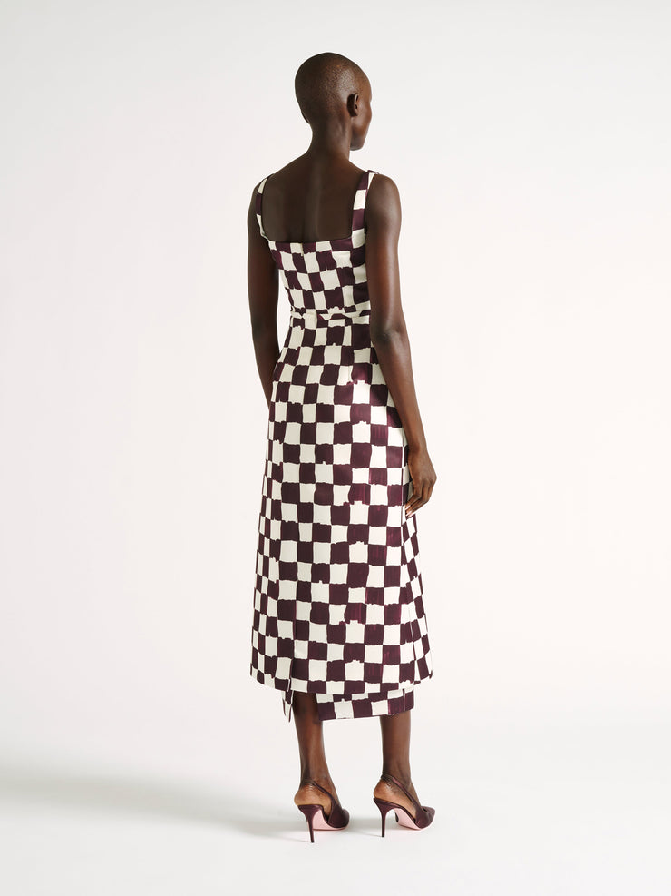 Sleek, linear, slim-fitting midi satin dress featuring a painterly checkerboard motif in a rich chocolate hue on an ivory base. Collagerie.com