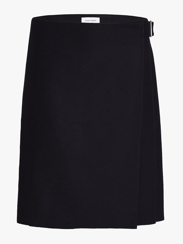 The Kate navy blue skirt by Issue Twelve is knee length with kilt pleats and a wrap front. In a wool and recycled cashmere perfect for Autumn Winter. Collagerie.com