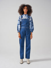 A slim wide-leg blue denim Seventy + Mochi dungaree with front pocket bib and adjustable straps. Perfect for every season. Collagerie.com