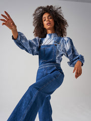 A slim wide-leg blue denim Seventy + Mochi dungaree with front pocket bib and adjustable straps. Perfect for every season. Collagerie.com